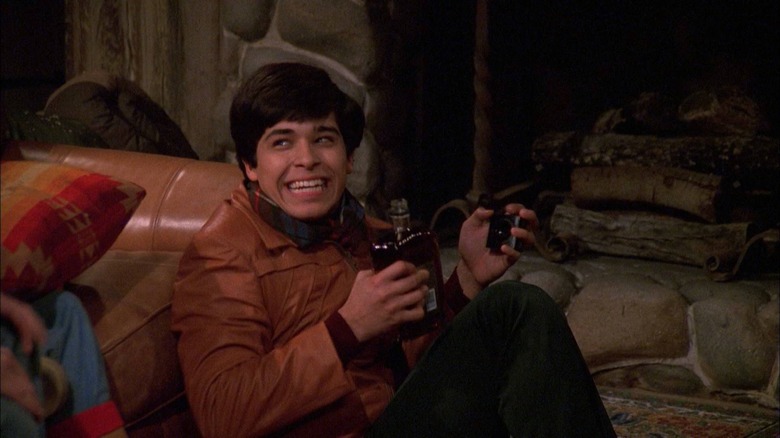 Fez smiling with a bottle of liquor