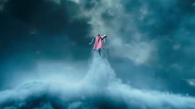 Supergirl flying into clouds holding body