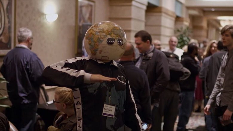 Man wearing a globe and sunglasses on his head in Behind the Curve