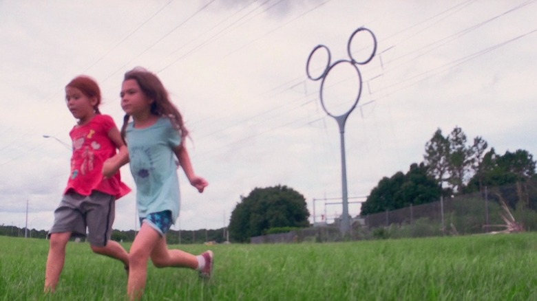 Jancey and Moonee running past telephone pole shaped like Mickey Mouse