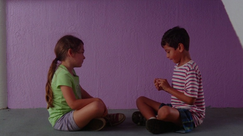 Moonee and Scooty sitting cross-legged in front of pink motel wall