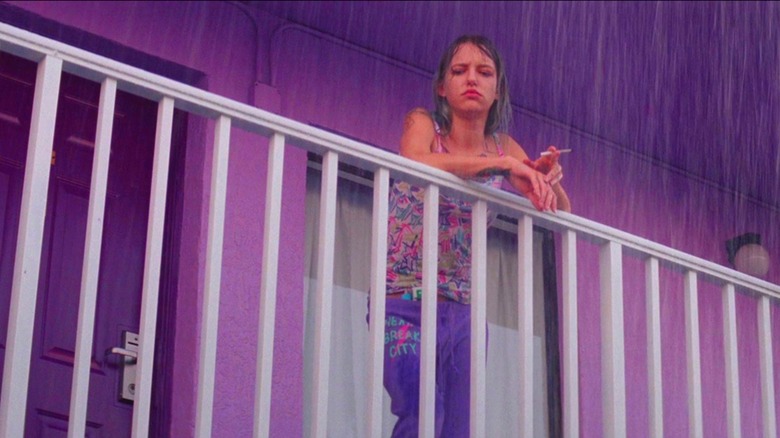 Halley leaning over motel railing in the pouring rain