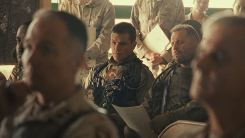 Matt Damon sits surrounded by soldiers