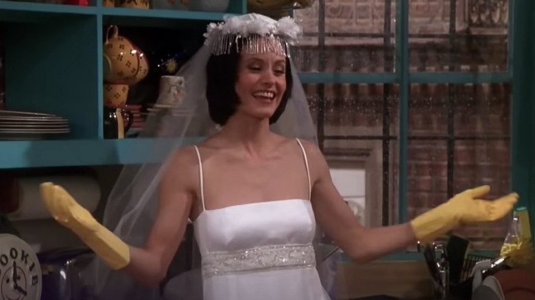 Monica in wedding dress cleans the kitchen