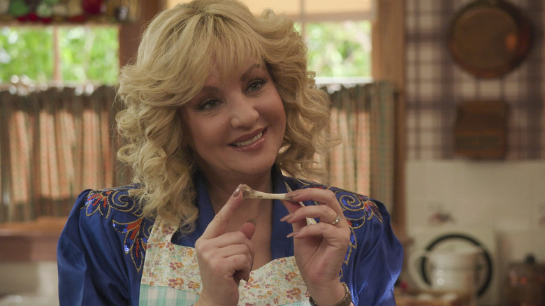 Beverly smiling and holding a bone as she cooks