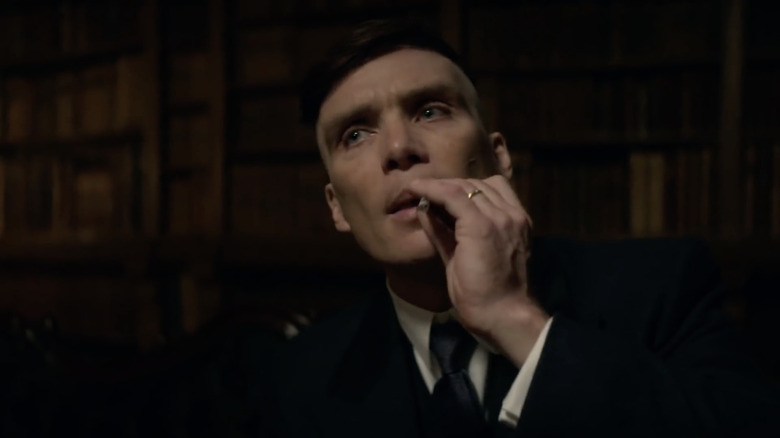 Tommy Shelby rubbing a cigarette on his lips