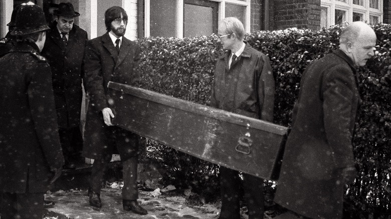 police carrying coffin from house