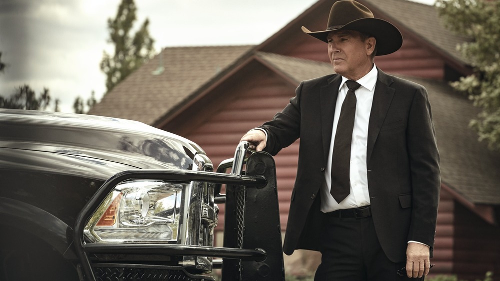 Kevin Costner in character as John Dutton wearing a suit and cowboy hat