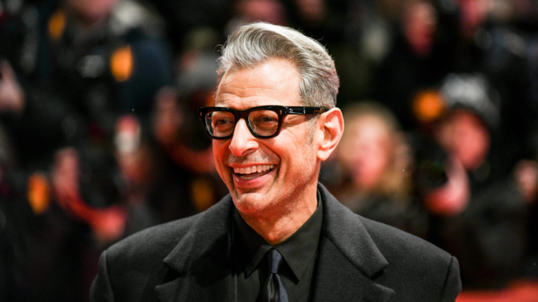 Jeff Goldblum wears a black suit and smiles