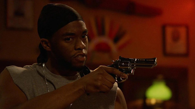 Chadwick Boseman holding a gun