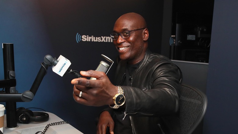 Lance Reddick sitting by a microphone