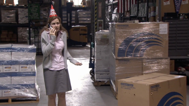 Pam Beesly wearing a party hat next to a box