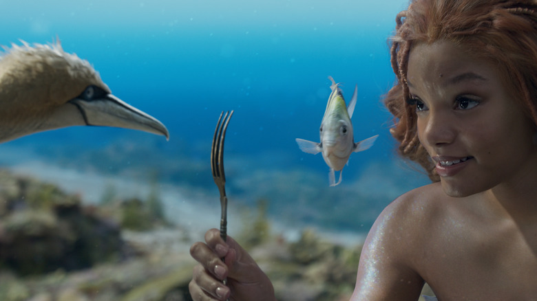 Ariel holding up a fork as Scuttle and Flounder look
