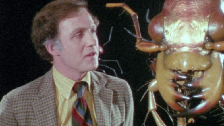 Lawrence Pressman stands next to oversized insect head
