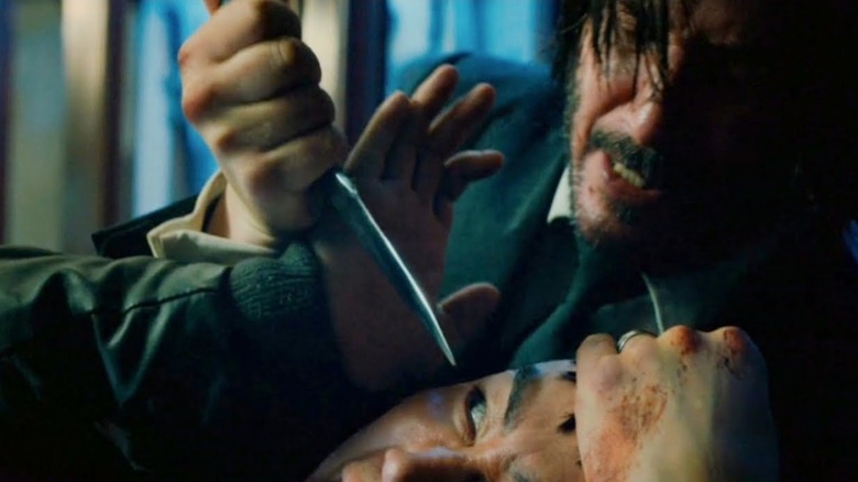 John Wick holding a knife over an assassin's eye