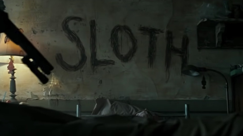 "Sloth" written on wall with body on bed