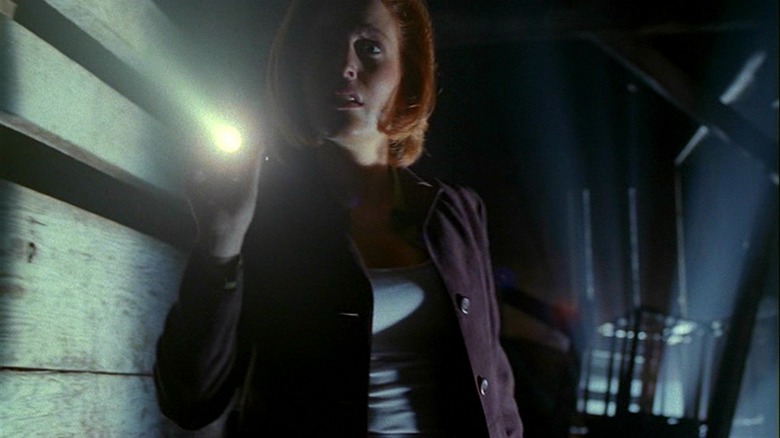 Scully in dark pointing flashlight 