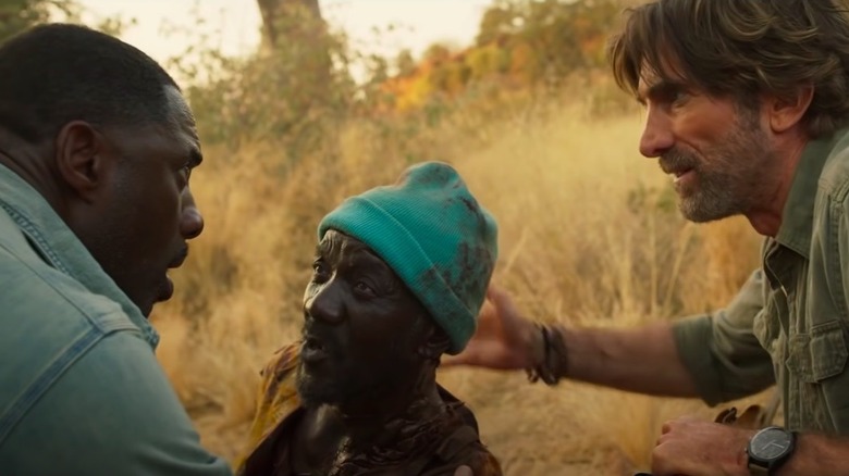 Idris Elba and Sharlto Copley comfort an injured man