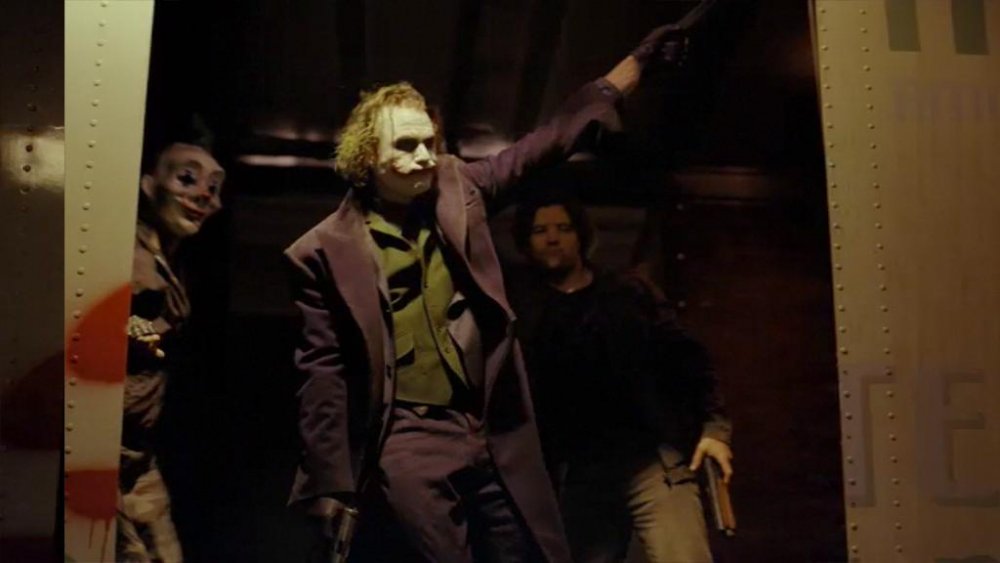 Heath Ledger as The Joker and his henchmen leaning in a truck in The Dark Knight