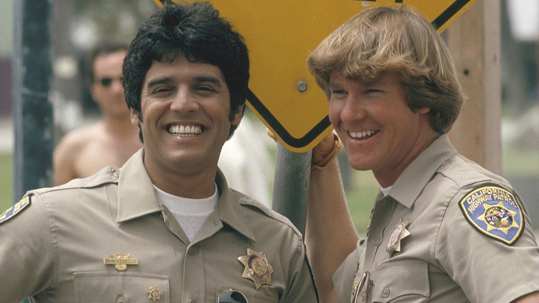 Baker and Ponch smile in front of a sign