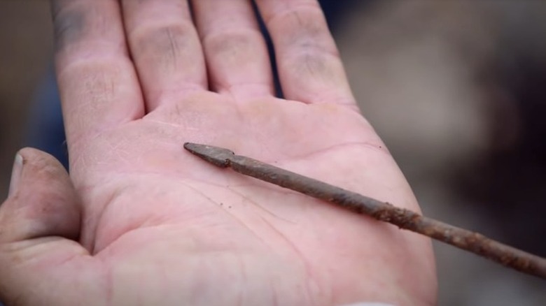 A hand holds an arrow-like artifact 