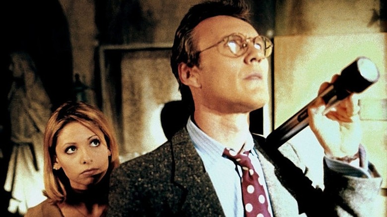 Buffy standing behind Giles who has flashlight