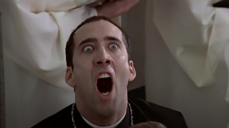 Nicolas Cage wide-eyed in priest robes