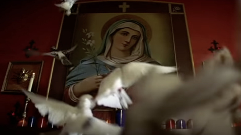 Pigeons flying in front of a Virgin Mary painting