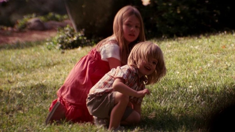 Cobb's children turn and face him while playing outside in the grass