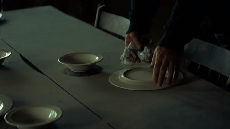 hands turn over plates and bowls on a dusty table