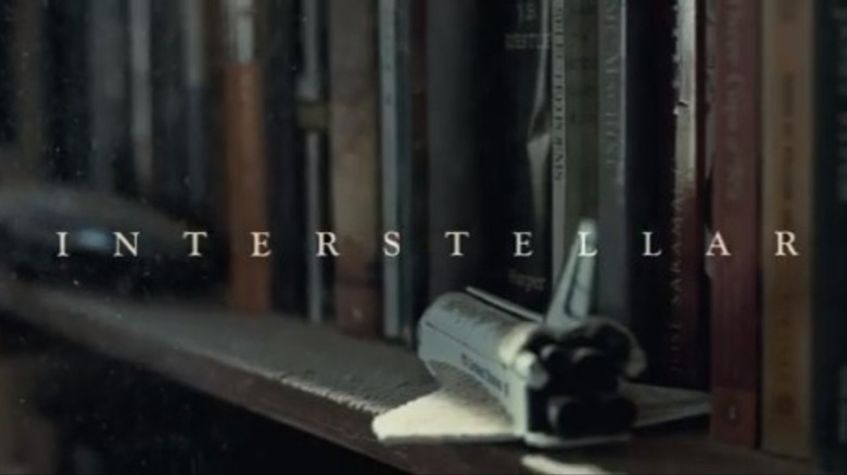 the word "Interstellar" appears in front of a dusty bookshelf