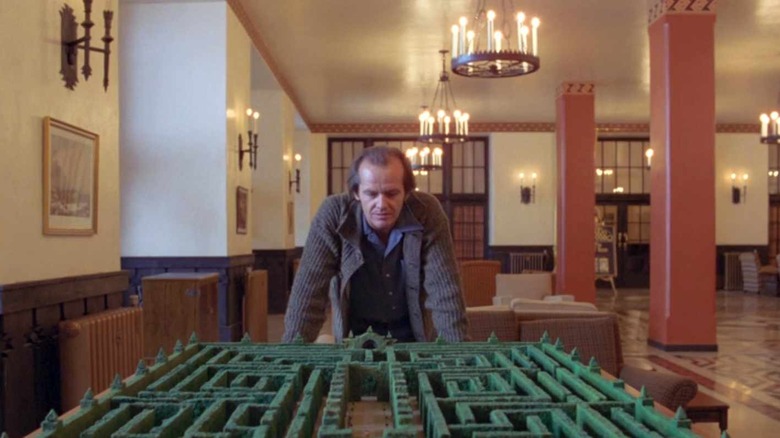 man overlooks a model of a hedge maze