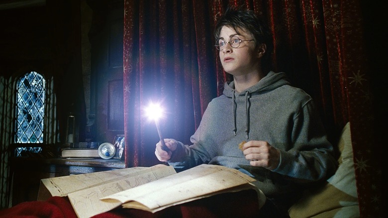 Harry using the Marauder's Map while in bed at Hogwarts