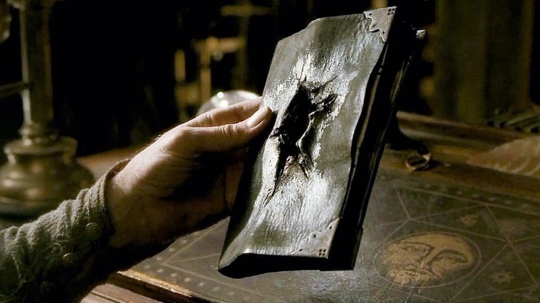 Albus Dumbledore holding Tom Riddle's destroyed diary