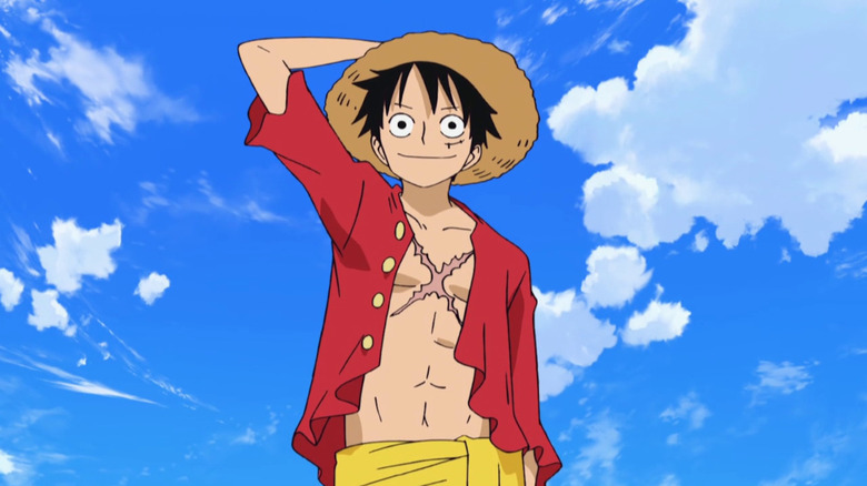 Luffy holds straw hat smiling