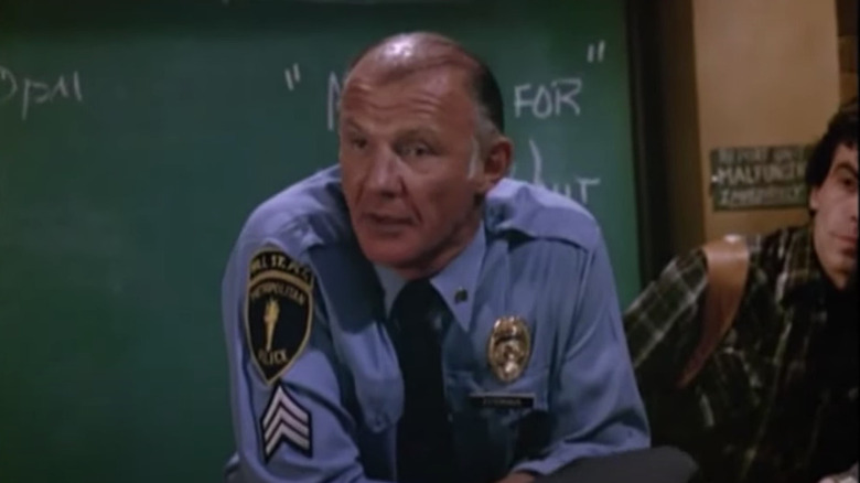 Cop stands at a podium with chalkboard