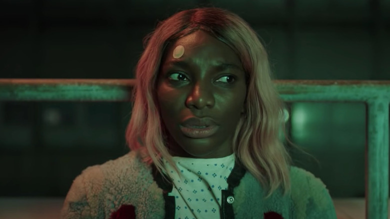 Michaela Coel sits against railing