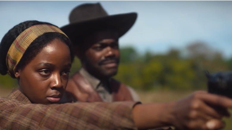 Cora shoots a gun in a field with Royal