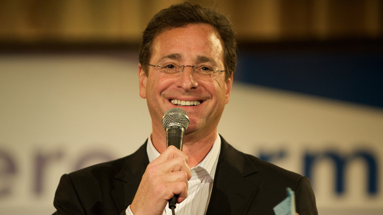 Bob Saget speaks into a microphone