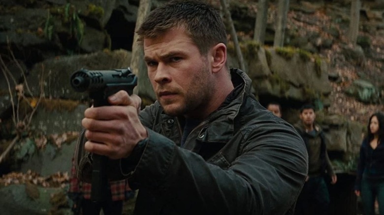 Hemsworth aims a gun