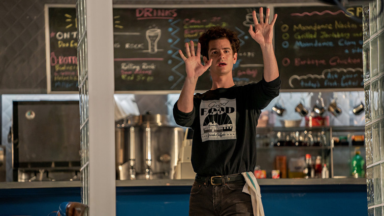 Andrew Garfield holding up his hands in a diner