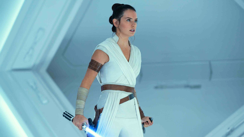 Rey grimacing and holding a blue lightsaber