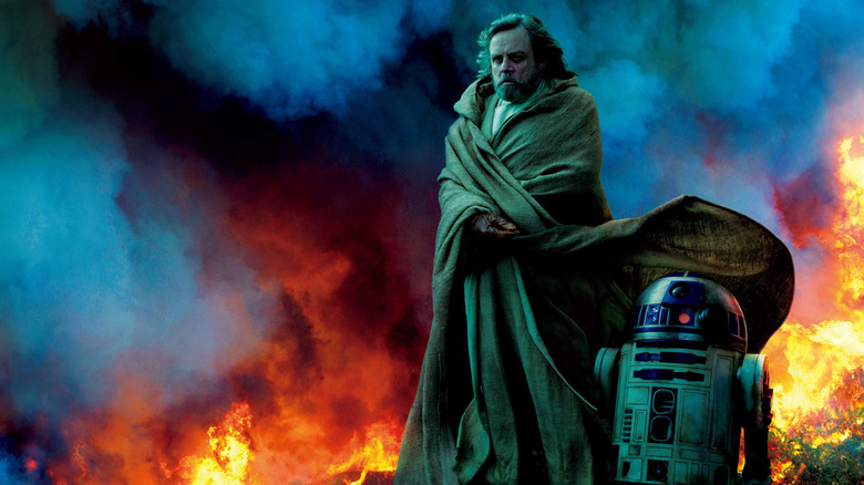 Luke Skywalker and R2-D2 standing by a raging fire