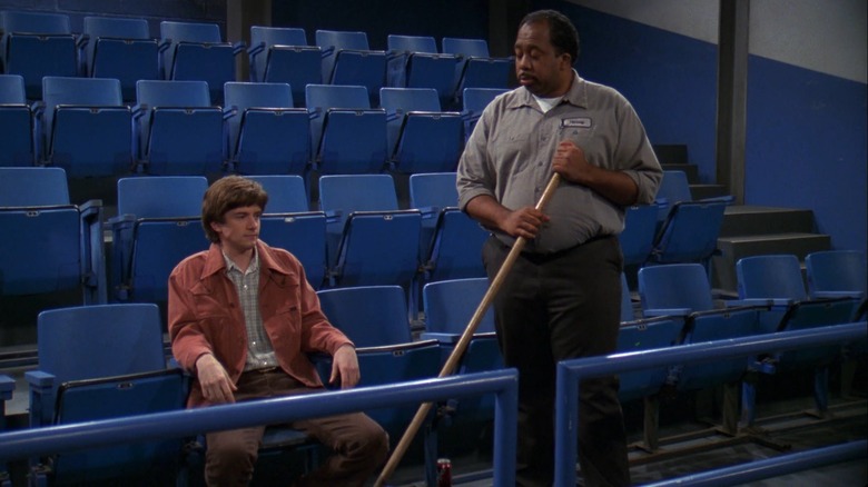 The janitor stands next to Eric 