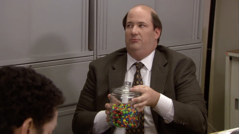 Kevin Malone holding a jar of candy