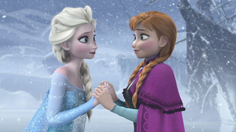 Elsa and Anna hold hands in the cold in Frozen (2013)