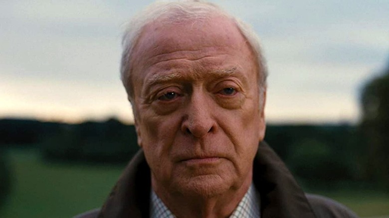 Michael Caine as Alfred scowling