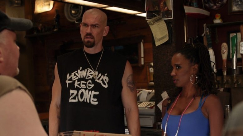 Steve Howey as Kevin Ball and Shanola Hampton as Veronica Fisher stand behind a bar