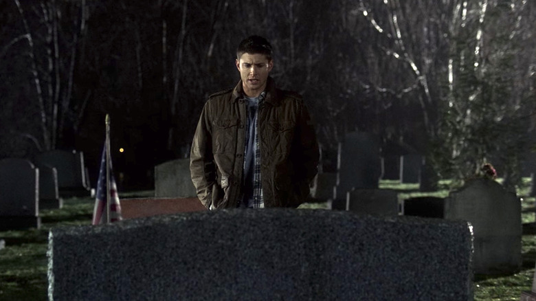 Dean Winchester standing in cemetery