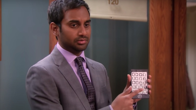 Aziz Ansari holding up a paper iPhone